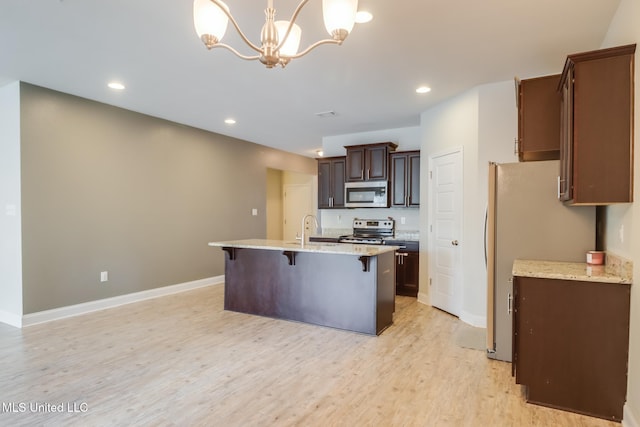15581 Ollie Ln, Biloxi, MS 39532 - kitchen featuring stainless steel appliances, a breakfast bar area, light wood-type flooring, recessed lighting, and a sink
