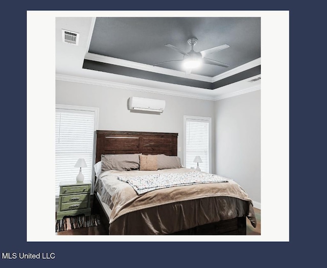 bedroom with a raised ceiling, crown molding, and a wall unit AC