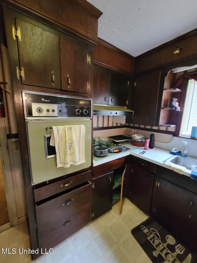 kitchen featuring oven, light flooring, a sink, and light countertops