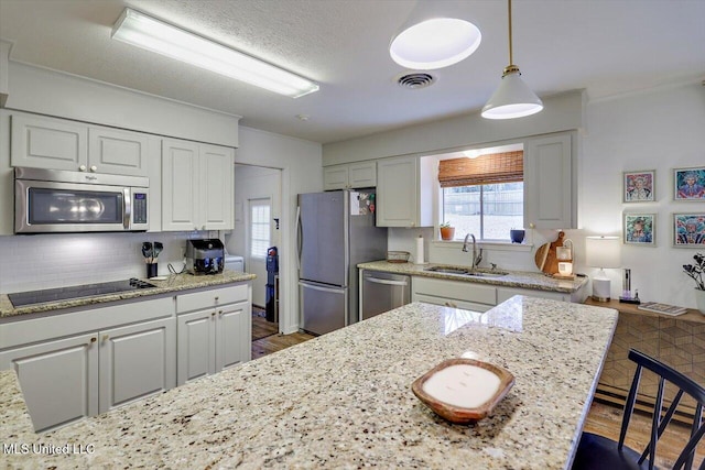 kitchen with stainless steel appliances, visible vents, decorative backsplash, white cabinetry, and a sink