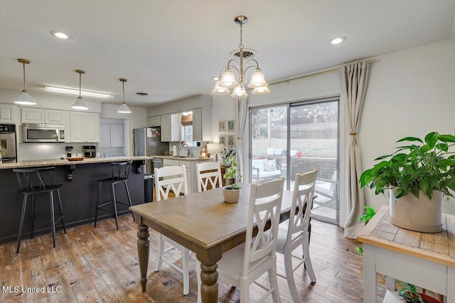 dining area featuring a chandelier, light wood finished floors, and recessed lighting