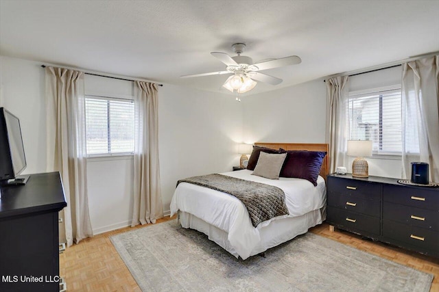 bedroom with multiple windows, baseboards, and a ceiling fan