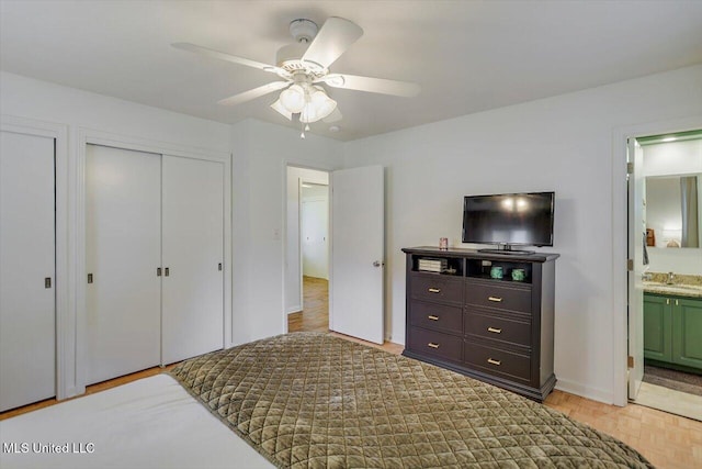 bedroom with ensuite bath, baseboards, ceiling fan, and a sink