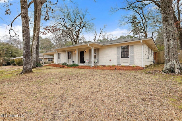 view of front of house featuring a front lawn, a porch, and brick siding