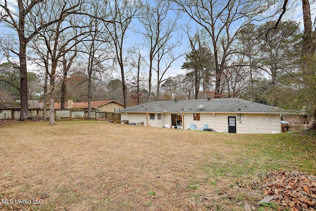 rear view of house featuring fence and a yard