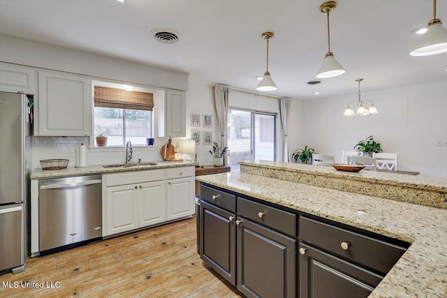 kitchen featuring stainless steel appliances, visible vents, light wood-style floors, white cabinets, and a sink