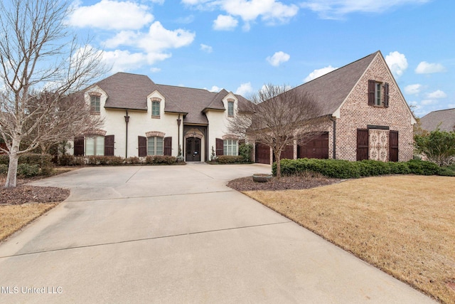 french country inspired facade with a garage and a front lawn