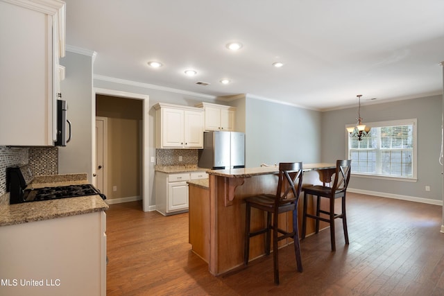 kitchen featuring light stone counters, appliances with stainless steel finishes, decorative light fixtures, hardwood / wood-style floors, and a kitchen island