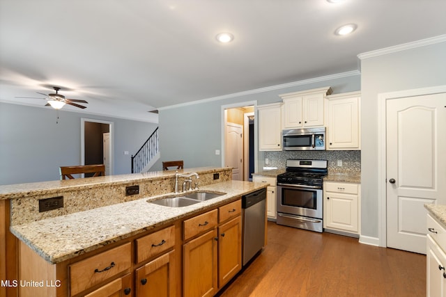 kitchen with ornamental molding, appliances with stainless steel finishes, dark wood-type flooring, and sink