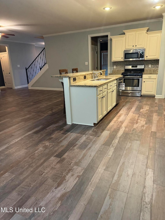 kitchen with stainless steel appliances, light stone counters, decorative backsplash, sink, and dark hardwood / wood-style floors