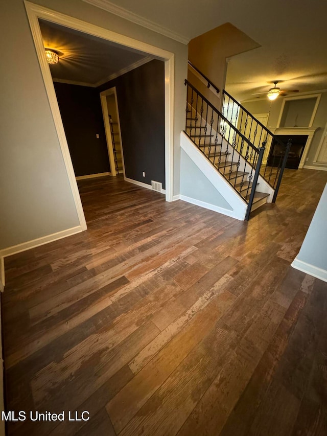 unfurnished living room with dark hardwood / wood-style flooring, ceiling fan, and crown molding