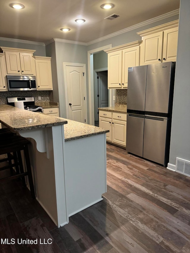 kitchen featuring light stone countertops, appliances with stainless steel finishes, decorative backsplash, and dark hardwood / wood-style floors