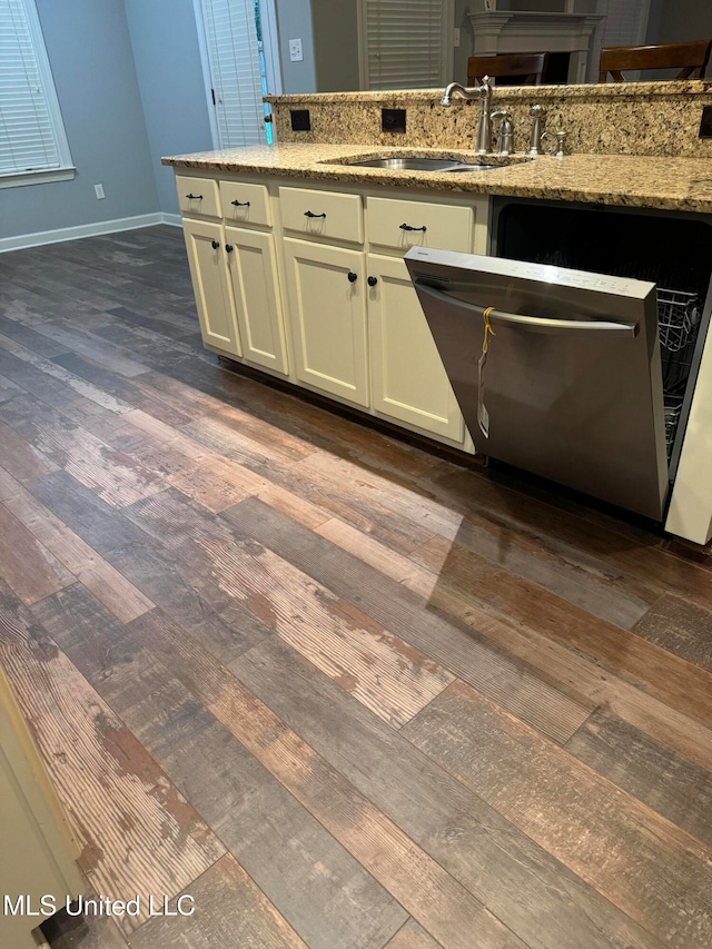 kitchen with dark hardwood / wood-style flooring, stainless steel dishwasher, sink, and light stone countertops