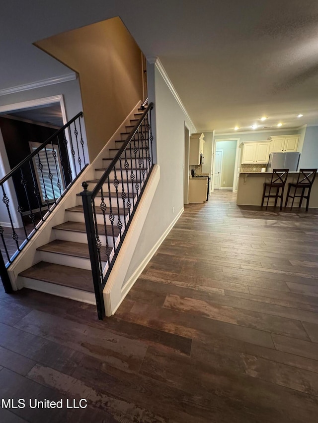 stairway with hardwood / wood-style floors and ornamental molding