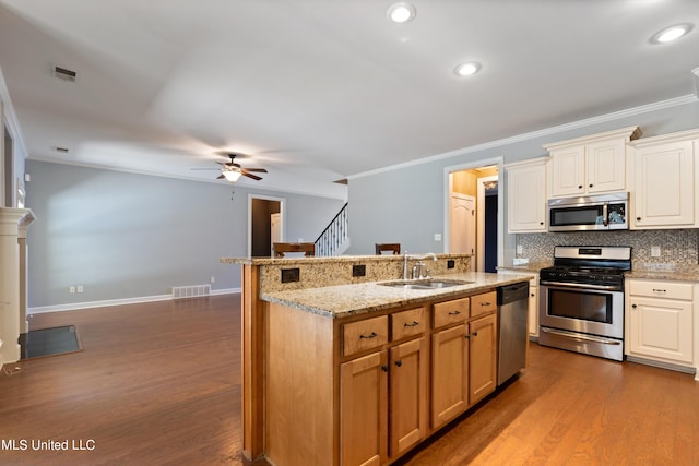 kitchen featuring wood-type flooring, crown molding, appliances with stainless steel finishes, sink, and ceiling fan