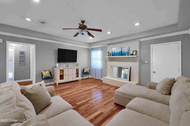 living room featuring ceiling fan, a fireplace, and wood-type flooring