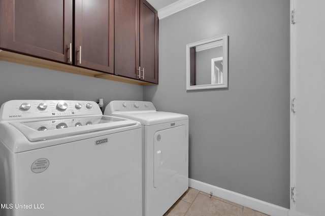 laundry area with cabinets, light tile patterned flooring, crown molding, and washer and clothes dryer