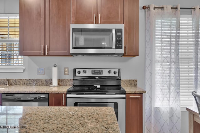 kitchen with appliances with stainless steel finishes and light stone counters