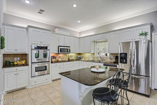 115 Victoria Pl, Brandon, MS 39042 - kitchen with appliances with stainless steel finishes, a sink, light tile patterned floors, a breakfast bar, and a center island