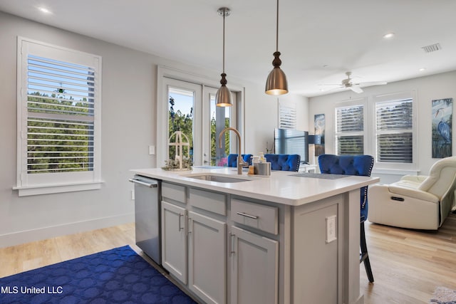 kitchen featuring a sink, stainless steel dishwasher, open floor plan, light wood-style floors, and light countertops