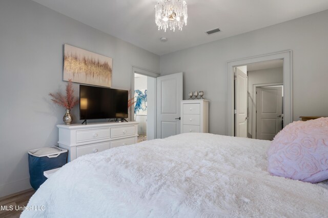 bedroom with baseboards, wood finished floors, visible vents, and a chandelier