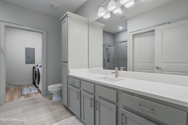 bathroom with toilet, electric panel, separate washer and dryer, a shower stall, and vanity