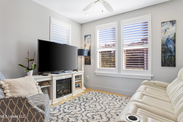 living room with baseboards, ceiling fan, and wood finished floors