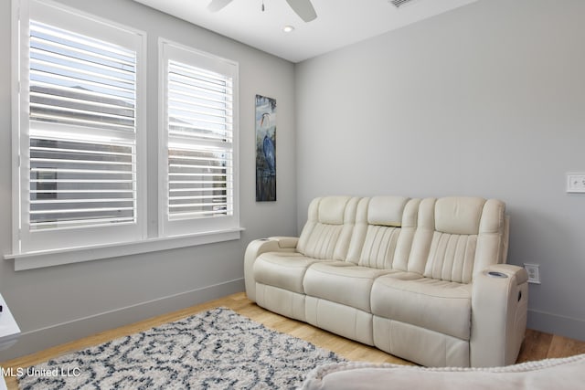 living area featuring ceiling fan, visible vents, baseboards, and wood finished floors