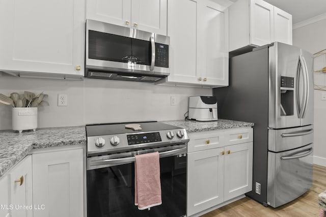 56 Oak Alley Ln, Long Beach, MS 39560 - kitchen featuring stainless steel appliances, white cabinets, light wood-style flooring, light stone countertops, and ornamental molding