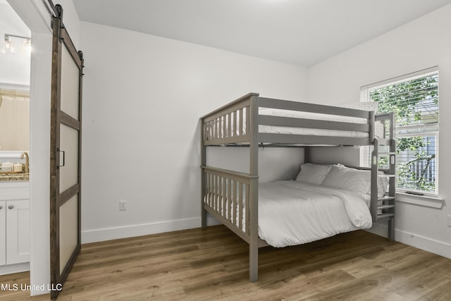 56 Oak Alley Ln, Long Beach, MS 39560 - bedroom with a barn door, baseboards, light wood finished floors, and a sink