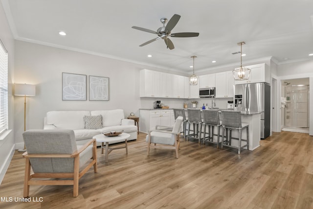 living room featuring a healthy amount of sunlight, ornamental molding, light hardwood / wood-style floors, and ceiling fan