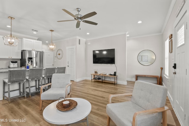 living room with crown molding, light hardwood / wood-style flooring, and ceiling fan with notable chandelier