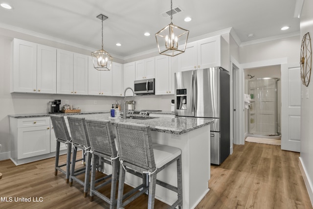 kitchen featuring a center island with sink, appliances with stainless steel finishes, white cabinetry, and light hardwood / wood-style floors