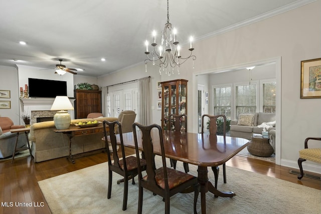 dining room with crown molding, ceiling fan, dark hardwood / wood-style flooring, and a stone fireplace