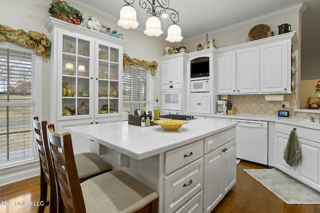 kitchen featuring pendant lighting, white appliances, white cabinets, and a kitchen island