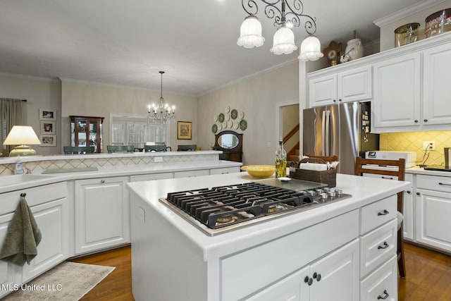 kitchen with white cabinetry, hanging light fixtures, a kitchen island, and appliances with stainless steel finishes