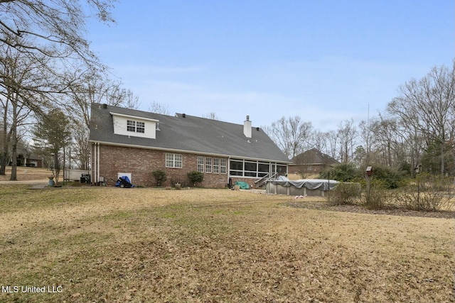 rear view of house featuring a yard, a covered pool, and a sunroom