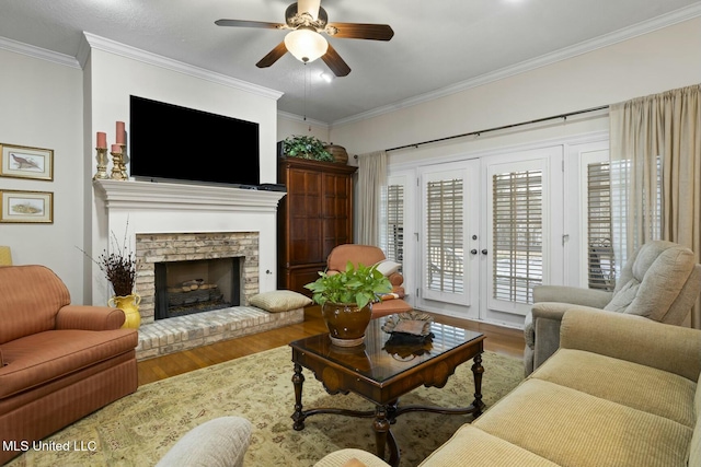 living room featuring wood-type flooring, ornamental molding, ceiling fan, a brick fireplace, and french doors