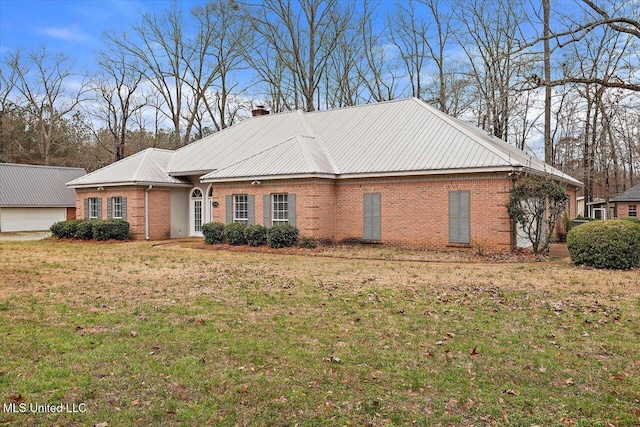 view of front of property featuring metal roof, brick siding, a chimney, and a front yard