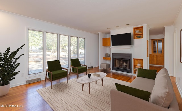 living area with wood finished floors, a wealth of natural light, and crown molding