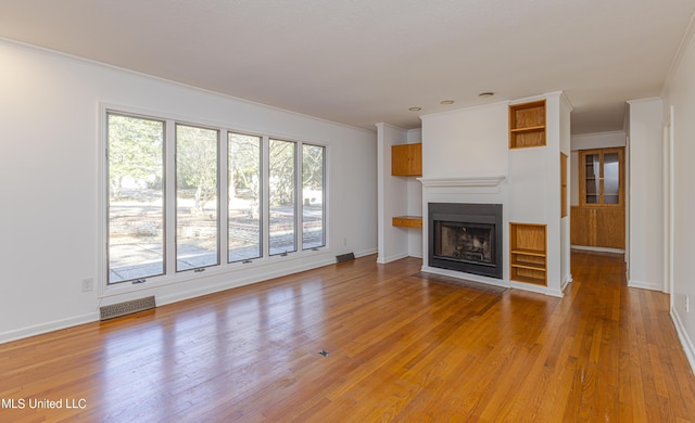 unfurnished living room with visible vents, a fireplace with flush hearth, light wood-style floors, ornamental molding, and baseboards