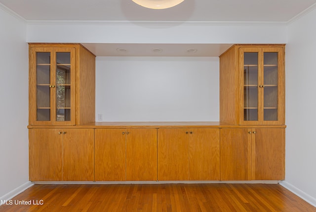 interior space featuring crown molding, baseboards, and wood finished floors