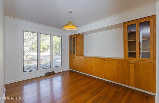 spare room featuring visible vents, dark wood finished floors, and crown molding