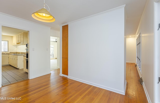 unfurnished room with light wood-style floors, ornamental molding, and baseboards