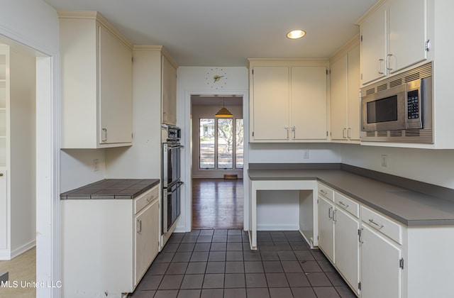 kitchen featuring recessed lighting, double wall oven, dark tile patterned flooring, stainless steel microwave, and dark countertops