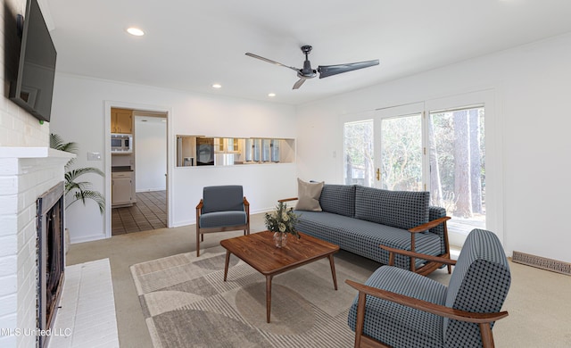 living area featuring light carpet, visible vents, a ceiling fan, a brick fireplace, and recessed lighting