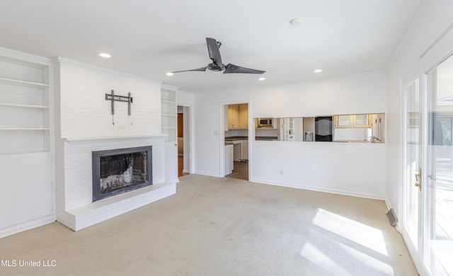 unfurnished living room featuring built in shelves, recessed lighting, light carpet, a fireplace, and a ceiling fan