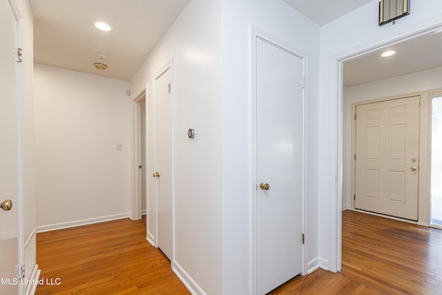 corridor with light wood finished floors, baseboards, visible vents, and recessed lighting