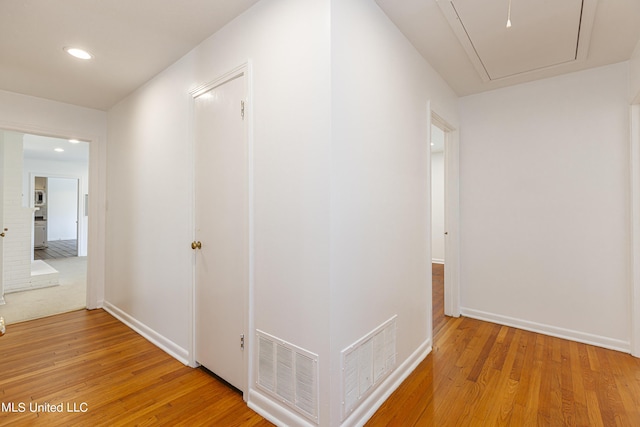 corridor with light wood-style flooring, recessed lighting, visible vents, baseboards, and attic access