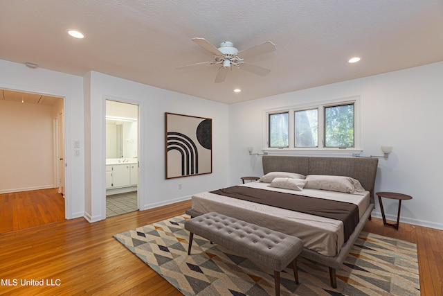 bedroom featuring ensuite bathroom, recessed lighting, wood finished floors, baseboards, and attic access